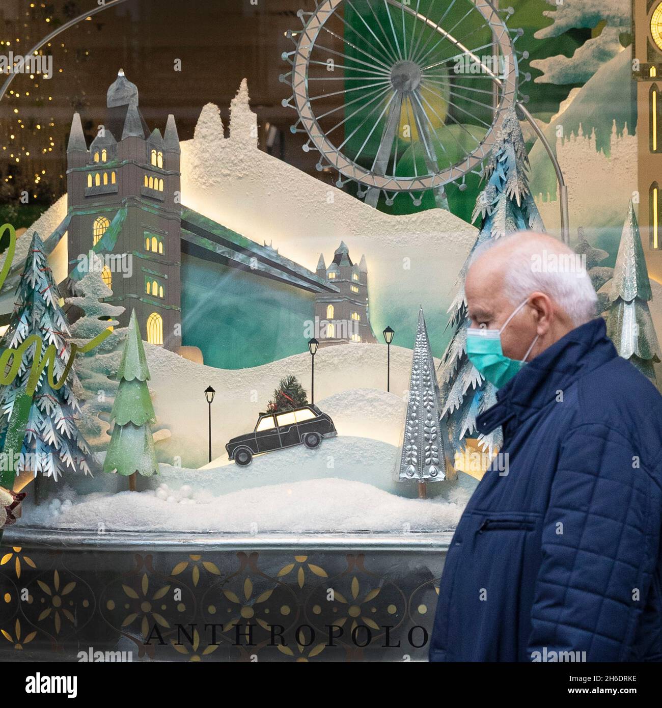 Le persone che indossano le maschere protettive Covid-19 passano davanti a una vetrina a tema natalizio su Regents Street, Londra. Foto Stock