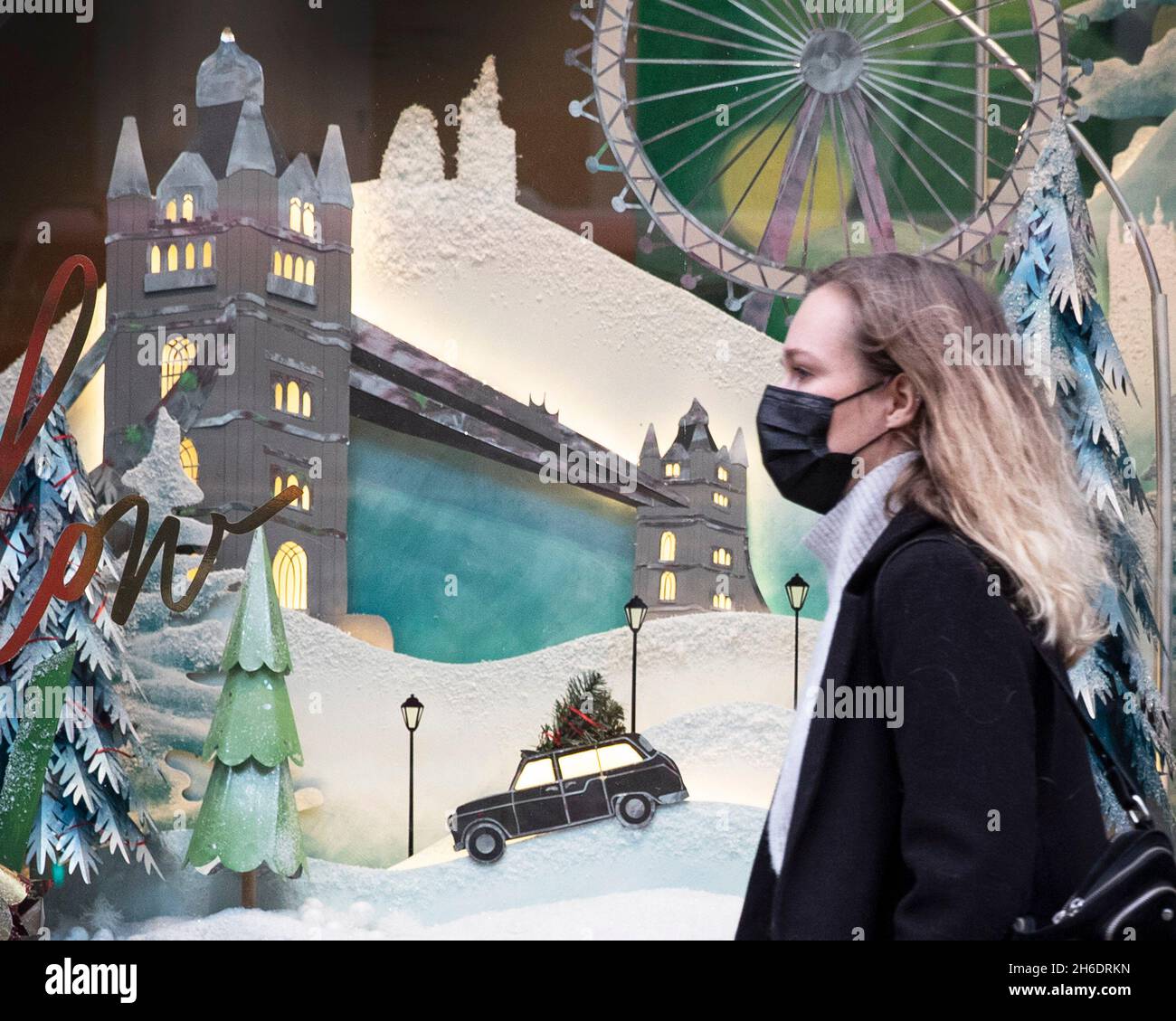 Le persone che indossano le maschere protettive Covid-19 passano davanti a una vetrina a tema natalizio su Regents Street, Londra. Foto Stock