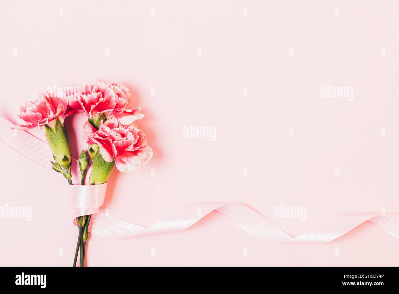 Sfondo rosa festoso con fiori bouquet e nastro di seta, spazio copia Foto Stock