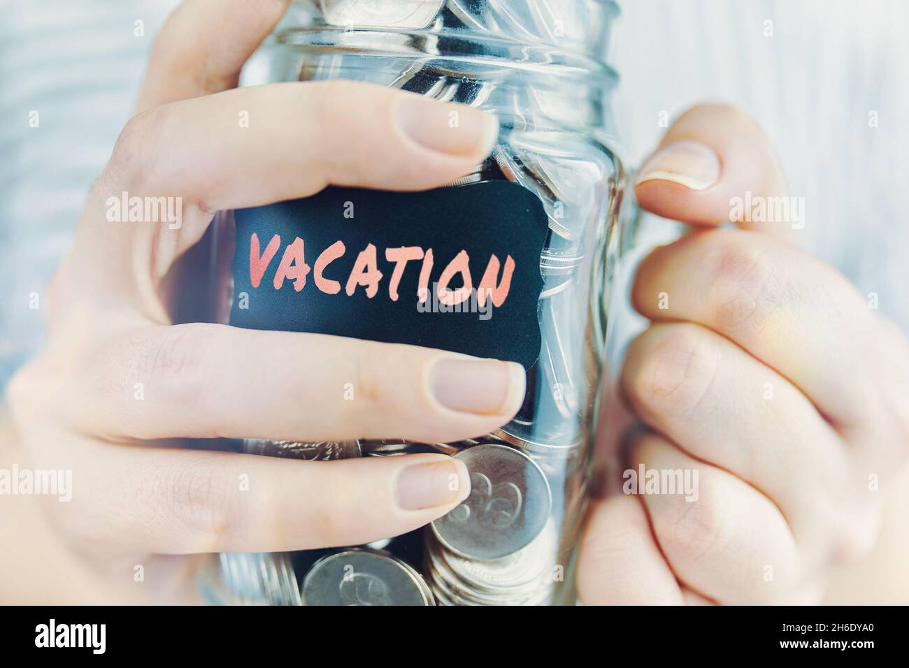 Donna tiene vaso di vetro di monete per le vacanze. Bottiglia con risparmio per viaggi e vacanze. Finanziario per intrattenimento e tempo libero in mare. Foto Stock