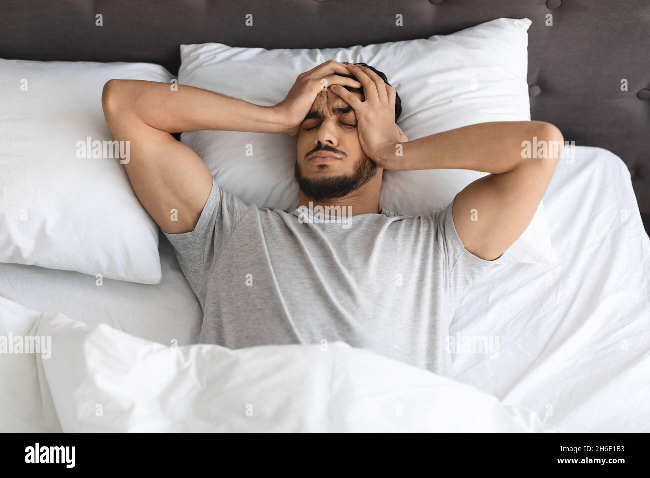 Il giovane ragazzo arabo riposato si sveglia al mattino con mal di testa Foto Stock