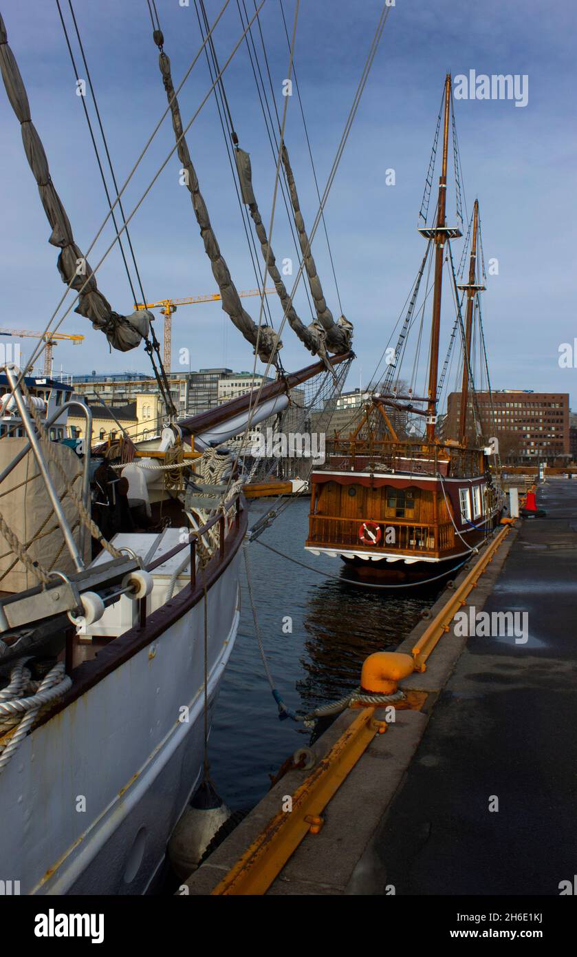 Porto di Oslo Norvegia brigantini a due alberi ormeggiati per attraccare con prua di un'altra nave in primo piano cielo blu nuvoloso verticale formato copia spazio alto navi Foto Stock