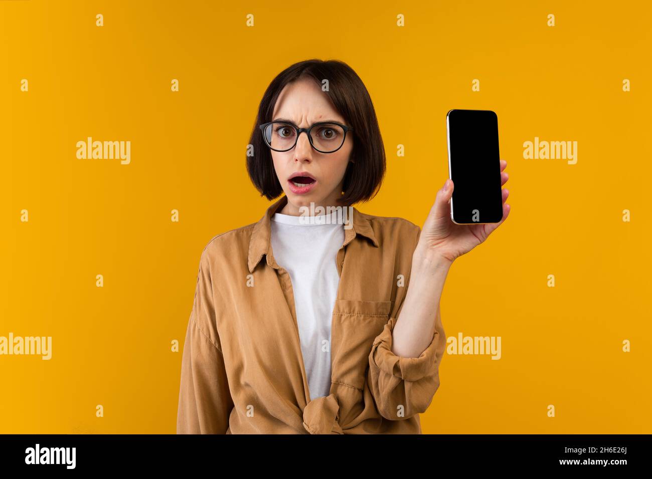 Insoddisfatto scioccato signora che tiene smartphone con schermo vuoto, mostrando app o sito web, essendo deluso, mockup Foto Stock
