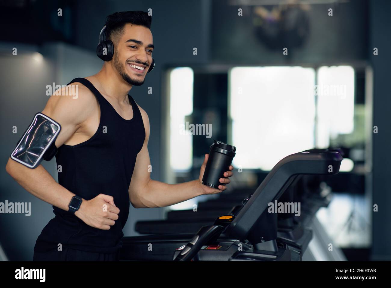 Happy Young Middle Eastern Male Athlete jogging sul tapis roulant in palestra Foto Stock