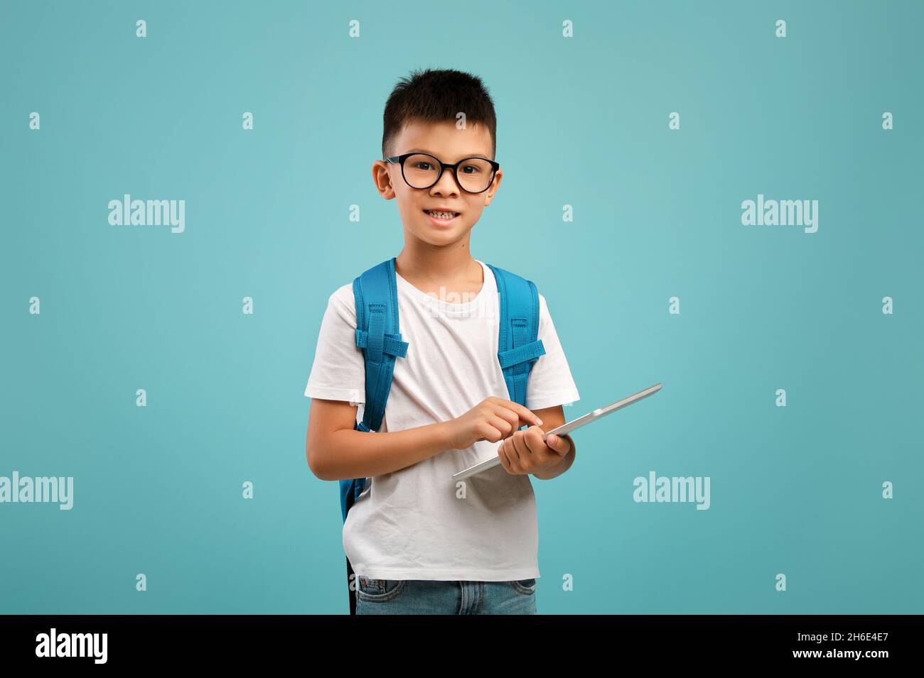 Gadget per lo studio. Carino ragazzo asiatico in Eyeglasses Holding Digital Tablet Foto Stock