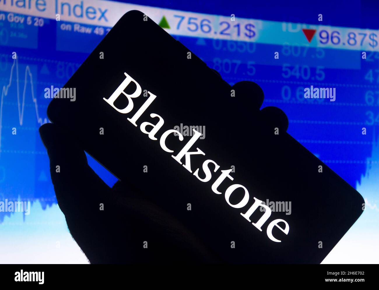 In questa foto è illustrato il logo Blackstone Group L.P. visualizzato sullo schermo di uno smartphone e un grafico del mercato azionario sullo sfondo. Foto Stock