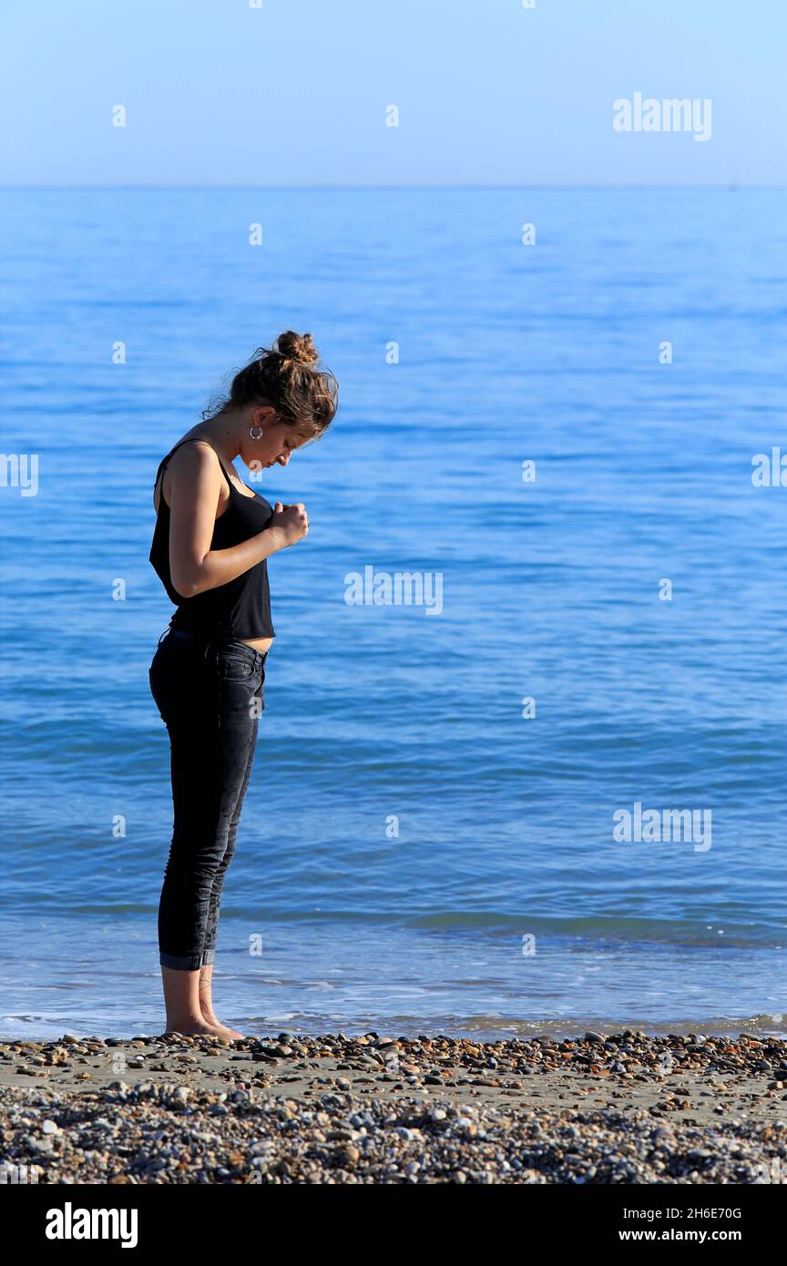 Giovane donna su una spiaggia mediterranea in inverno in Occitanie, Francia Foto Stock