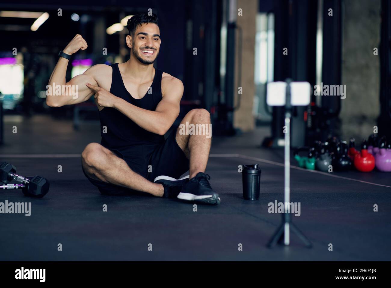 Fitness Blog. Giovane atleta mediorientale che cattura contenuti video in palestra Foto Stock