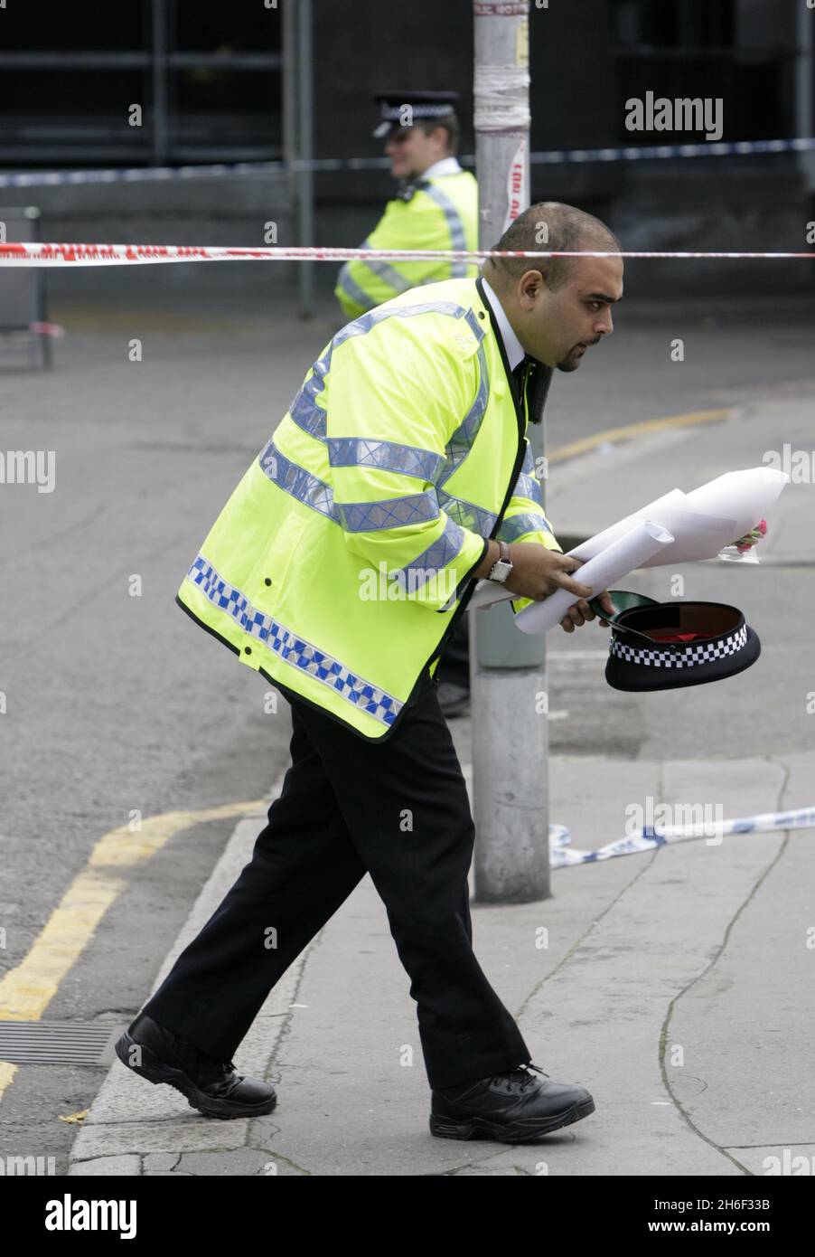 Un ufficiale di polizia che posa fiori alla scena dell'omicidio a Mann Close, Croydon. Due ragazze adolescenti sono state arrestate dopo che la ragazza di 17 anni Sian Simpson è stata pugnalata a morte poco prima delle 20 della notte scorsa. Foto Stock