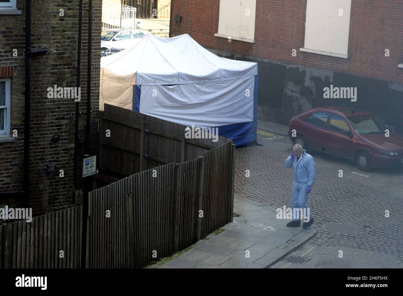 Un ufficiale di polizia forense assiste la scena a Kilburn, a nord di Londra, dopo la scoperta di un corpo avvolto in fogli. Gli ufficiali sono stati chiamati in scena alle 7.10, dopo che un membro del pubblico ha fatto la scoperta dietro alcuni negozi. Foto Stock
