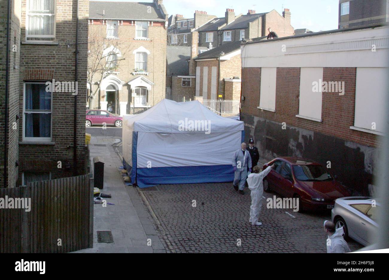 Un ufficiale di polizia forense assiste la scena a Kilburn, a nord di Londra, dopo la scoperta di un corpo avvolto in fogli. Gli ufficiali sono stati chiamati in scena alle 7.10, dopo che un membro del pubblico ha fatto la scoperta dietro alcuni negozi. Foto Stock