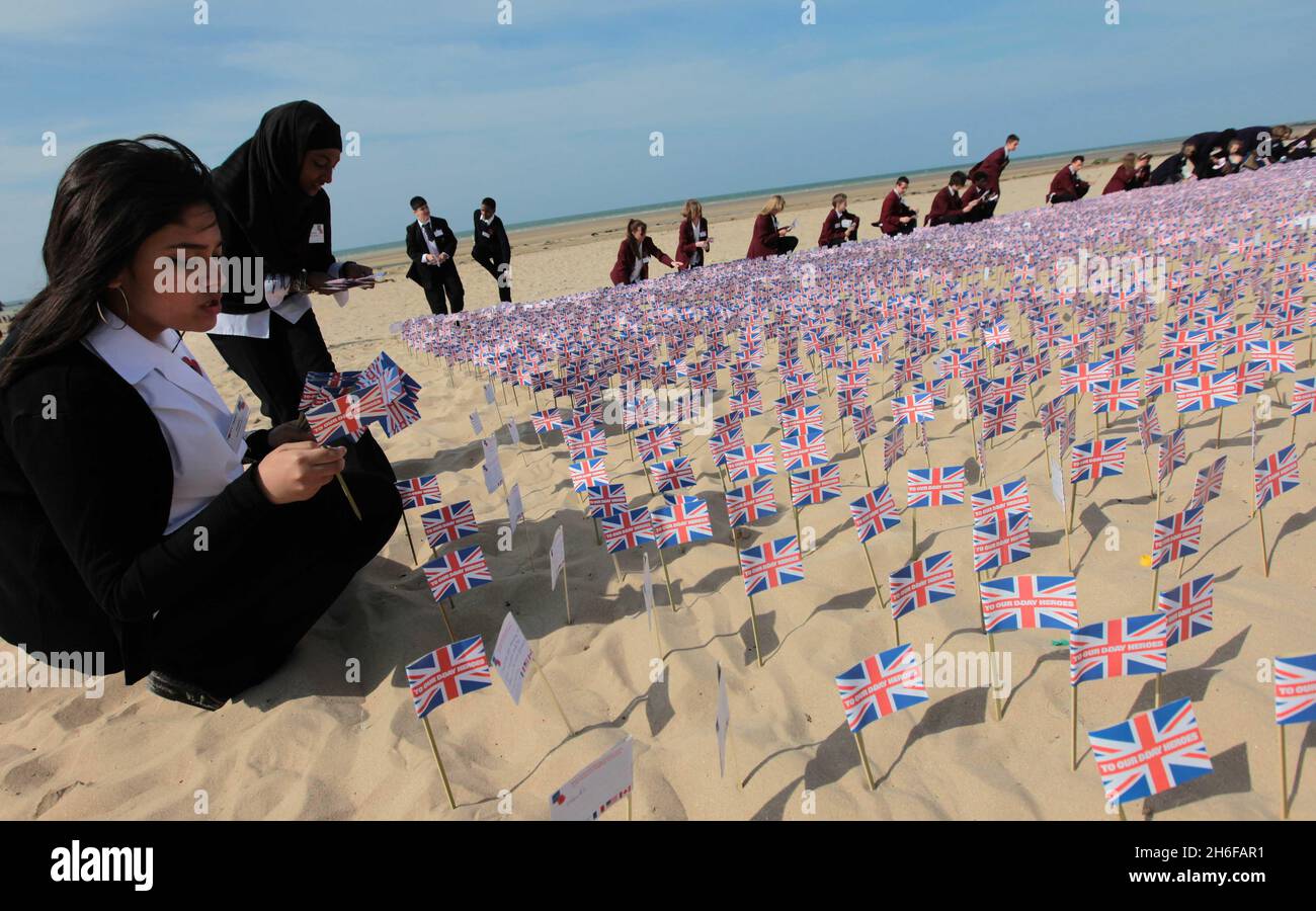 Le studentesse Fateha Chowdhury (14 anni) e Tasmina Hussain (15 anni) della Morpeth School di Bethnal Green, Londra, piazzando bandiere con centinaia di altri Union Jack Flags recanti messaggi dal pubblico britannico, hanno messo su Gold Beach ad Asnelles, Francia oggi, per ricordare coloro che hanno perso la vita nella seconda Guerra Mondiale. Foto Stock