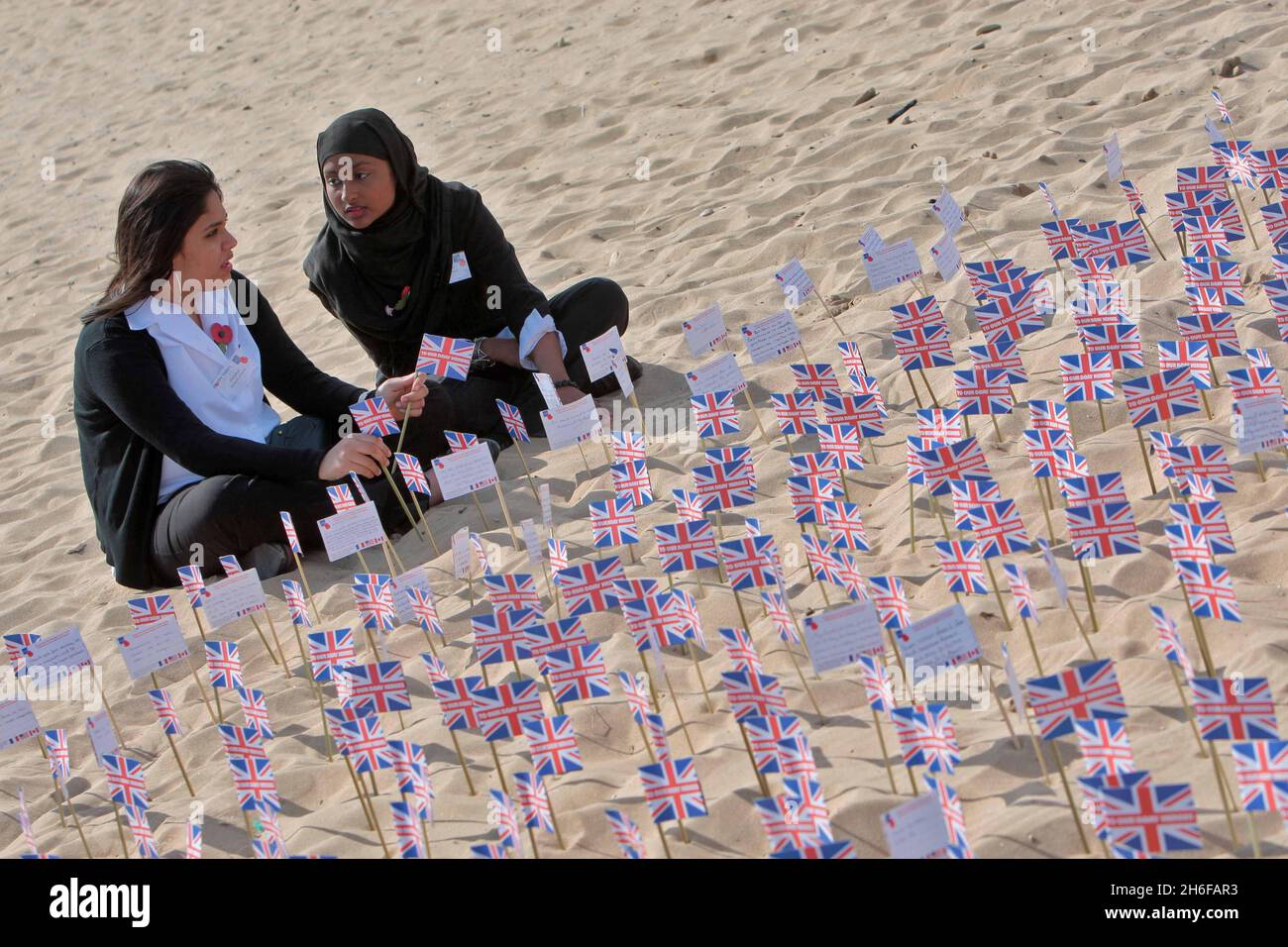 Le studentesse Fateha Chowdhury (14 anni) e Tasmina Hussain (15 anni) della Morpeth School di Bethnal Green, Londra, piazzando bandiere con centinaia di altri Union Jack Flags recanti messaggi dal pubblico britannico, hanno messo su Gold Beach ad Asnelles, Francia oggi, per ricordare coloro che hanno perso la vita nella seconda Guerra Mondiale. Foto Stock