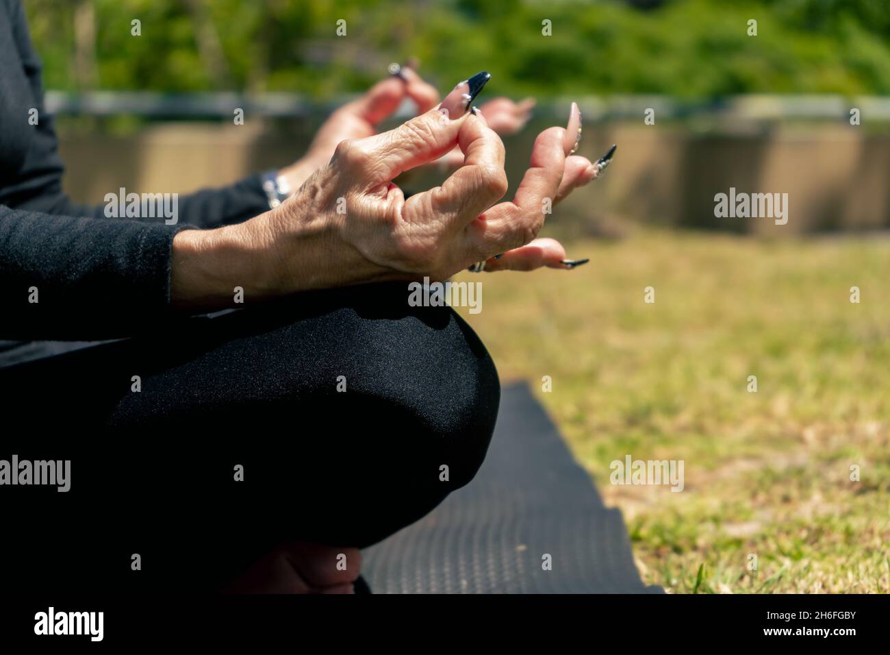 primo piano delle mani di una donna matura che pratica lo yoga e si siede nella posizione del loto. Concetto di concentrazione, vita sana. Foto Stock