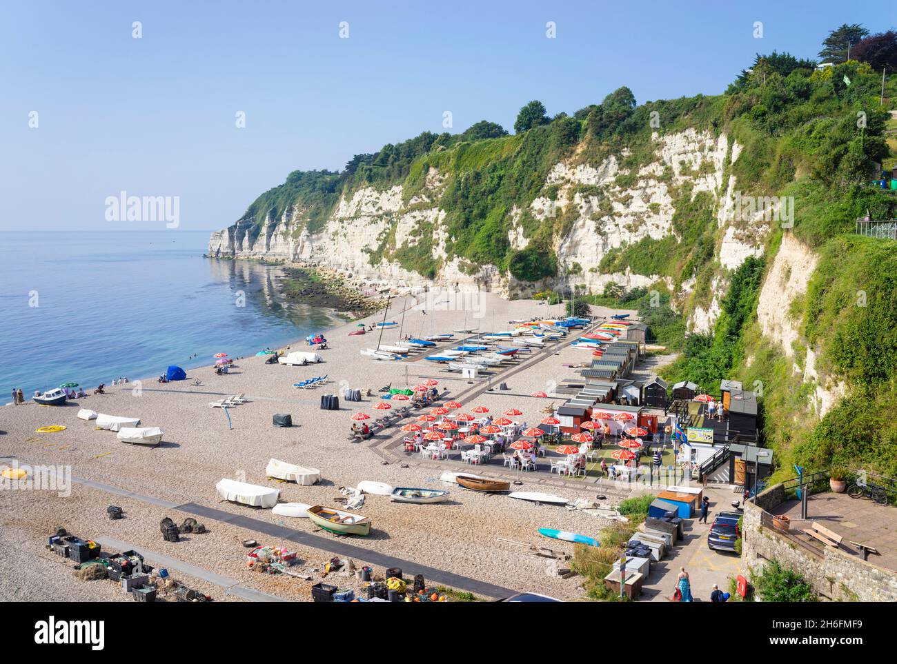 Beer Devon un sacco di persone si sono seduti sulla spiaggia di ciottoli tra le barche da pesca sulla spiaggia di Beer Devon Inghilterra UK GB Europa Foto Stock
