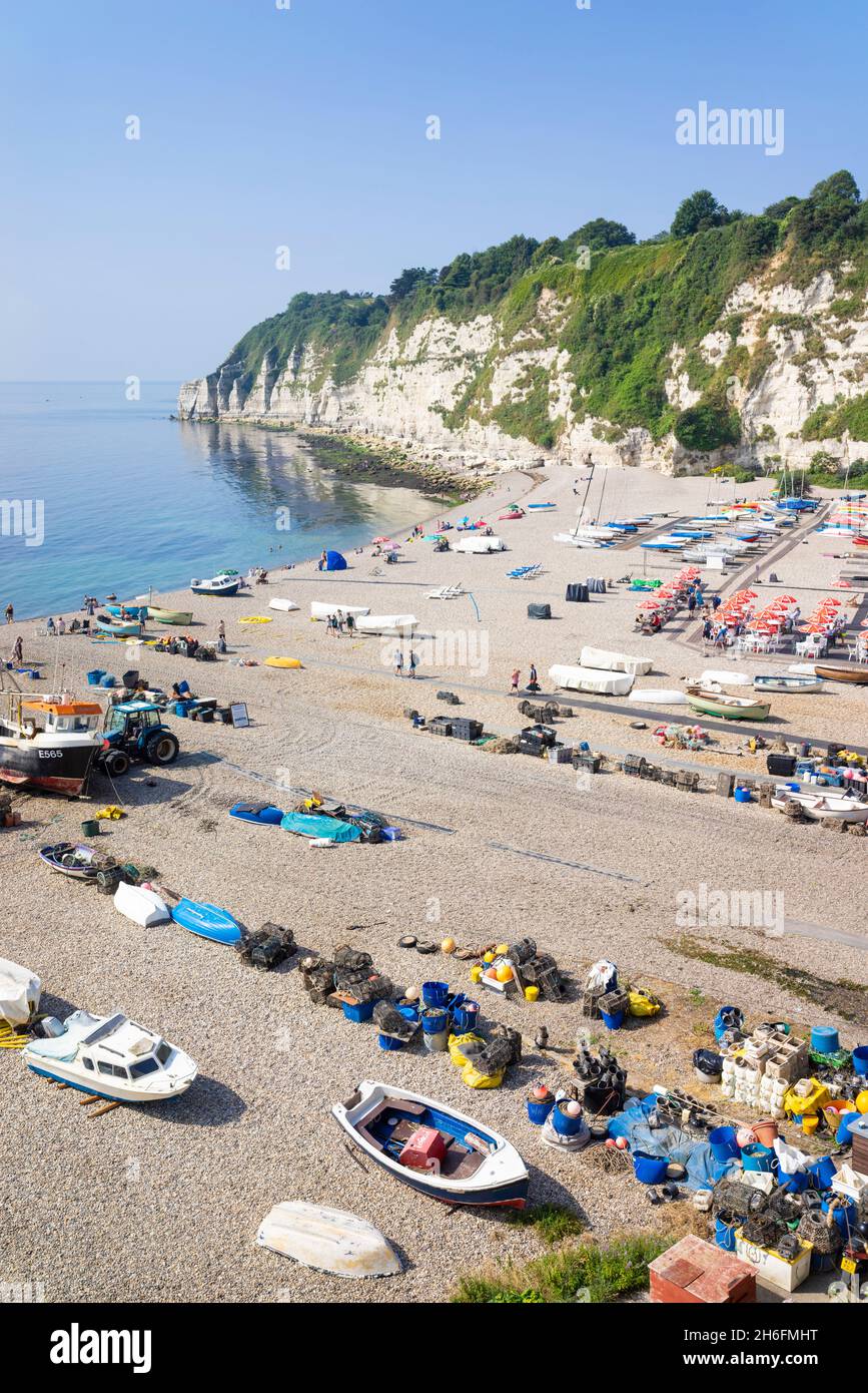 Beer Devon un sacco di persone si sono seduti sulla spiaggia di ciottoli tra le barche da pesca sulla spiaggia di Beer Devon Inghilterra UK GB Europa Foto Stock