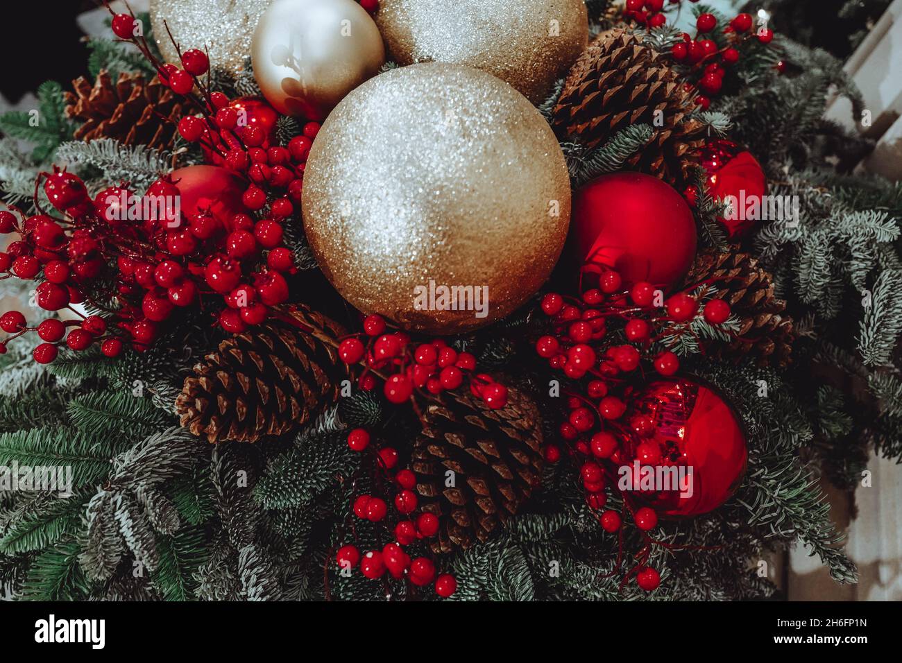 Decorazione natalizia con giocattoli natalizi palle dorate, bacche rosse e coni forestali. Festa invernale. Concetto di anno nuovo. Foto Stock