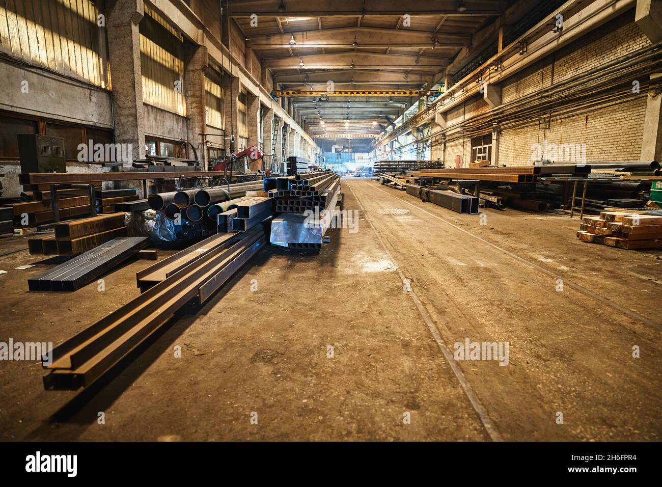 Colpo grandangolare di vecchia fabbrica lunga di lavorazione dei metalli con metallo e pezzi di ricambio Foto Stock