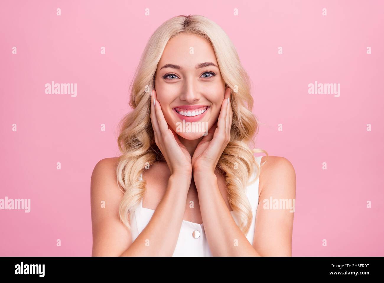 Foto di giovane ragazza attraente felice sorriso positivo mani toccare guance pelle isolato su sfondo rosa colore Foto Stock