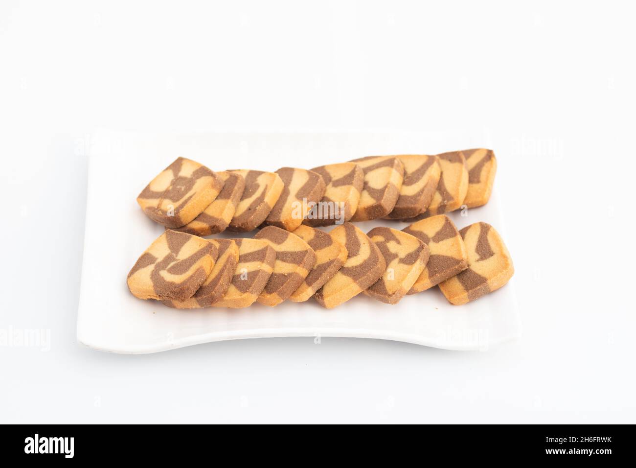 Biscotti a forma quadrata con gocce di cioccolato serviti in vassoio bianco. Isolato su sfondo bianco con spazio di copia per testo personalizzato. Vista laterale e selettiva Foto Stock