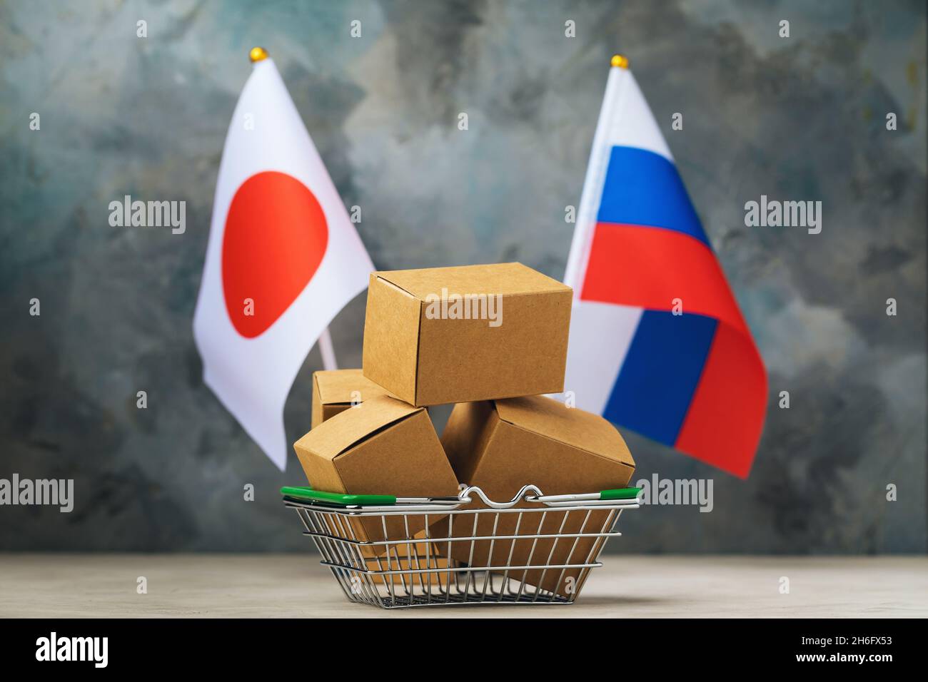 Varie scatole in un cestino di cibo e due bandiere su un background astratto, il concetto di commercio tra Giappone e Russia Foto Stock