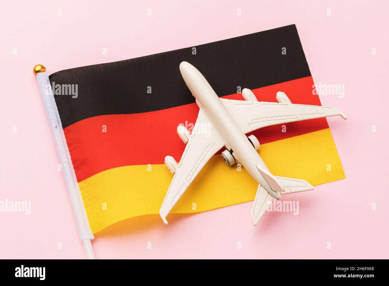 Bandiera della Germania e un aereo giocattolo su sfondo rosa, concetto sul tema del viaggio nel paese Foto Stock