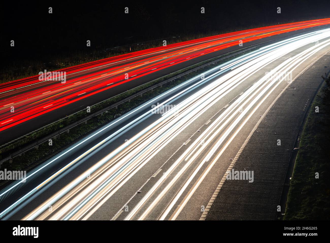 Percorsi leggeri da un'autostrada o autostrada trafficata di notte che mostrano il movimento del traffico all'ora di punta. Il traffico sembra guidare a sinistra Foto Stock