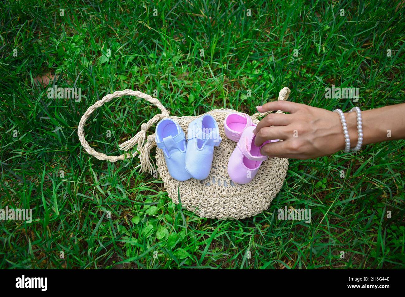Futura mamma che tiene scarpe rosa per bambini in un parco Foto Stock