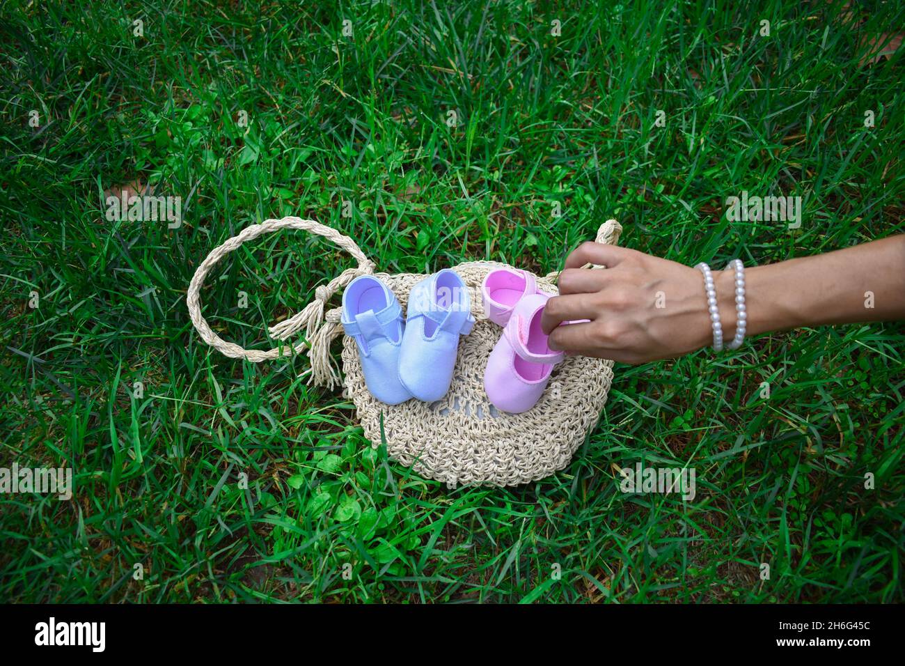 Futura mamma che tiene scarpe rosa per bambini in un parco Foto Stock