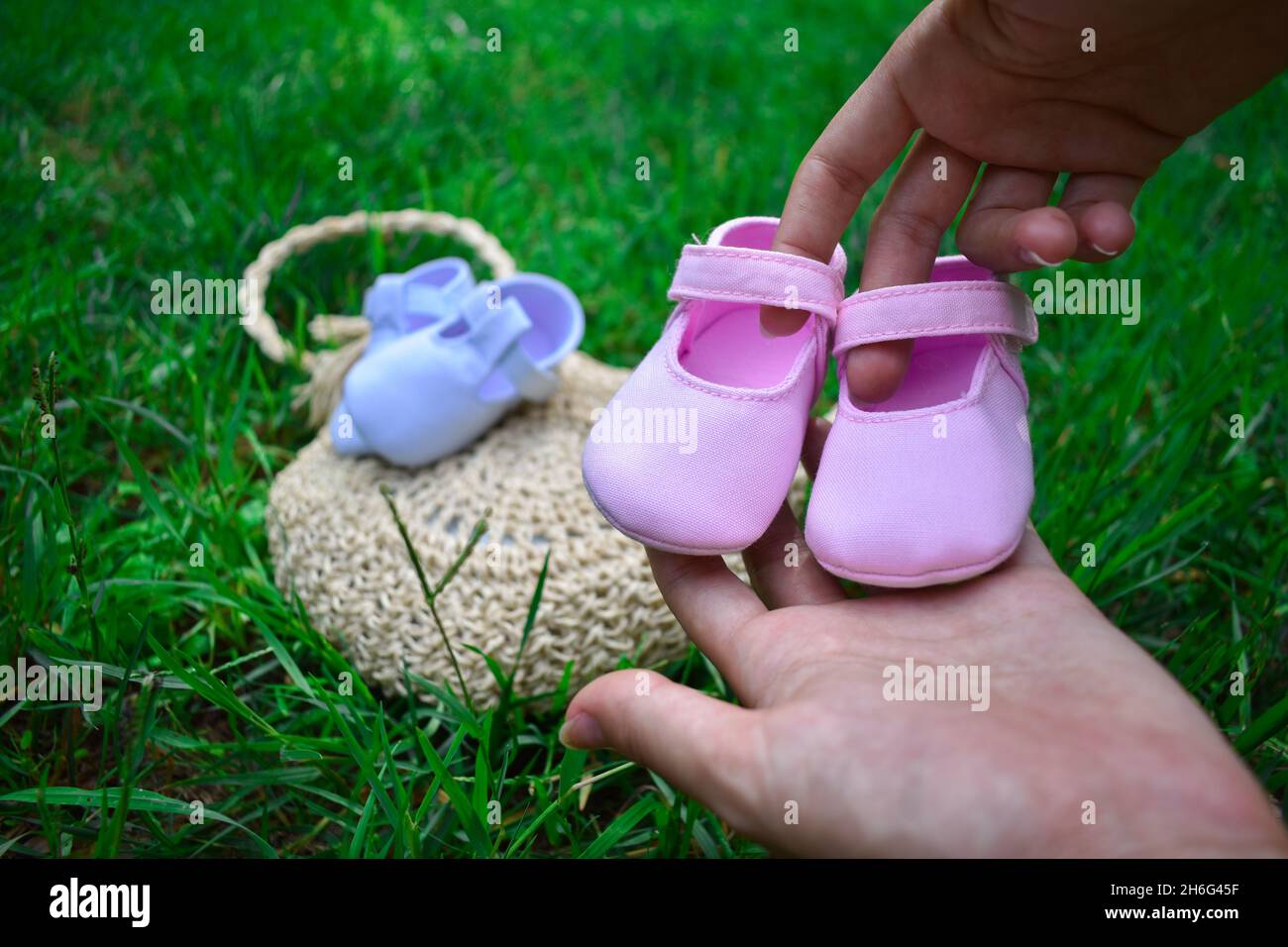 Futura mamma che tiene scarpe rosa per bambini in un parco Foto Stock