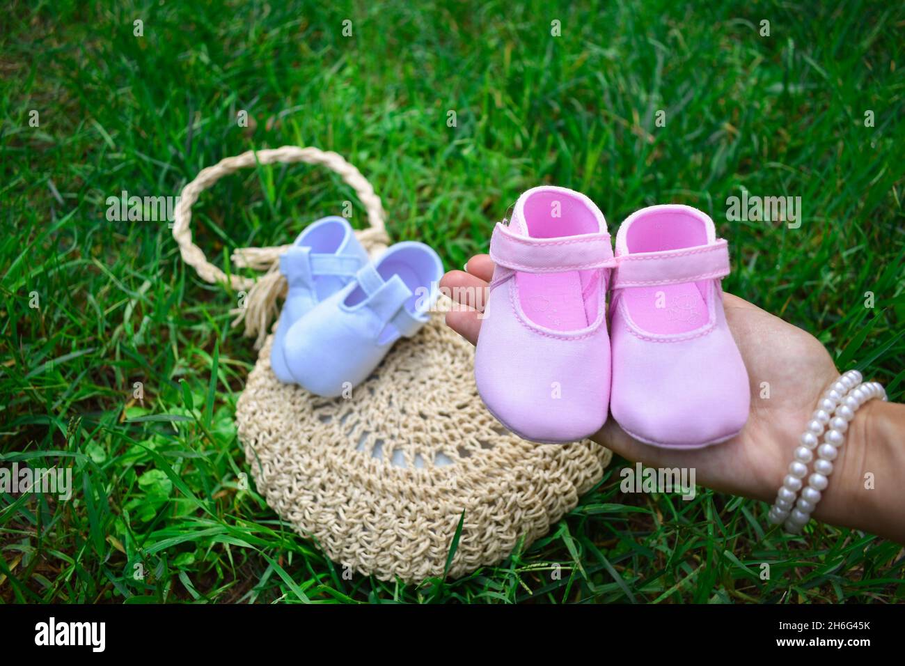 Futura mamma che tiene scarpe rosa per bambini in un parco Foto Stock