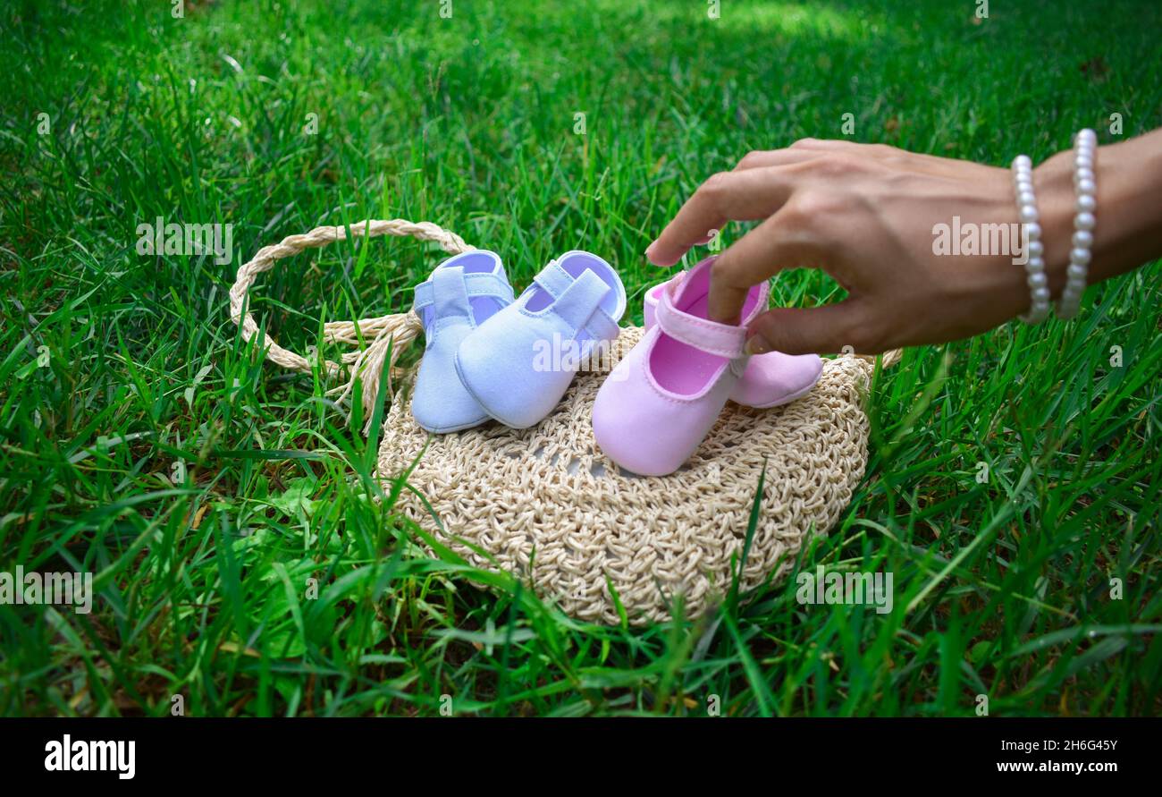 Una futura mamma che tiene scarpe rosa per bambini in un parco Foto Stock
