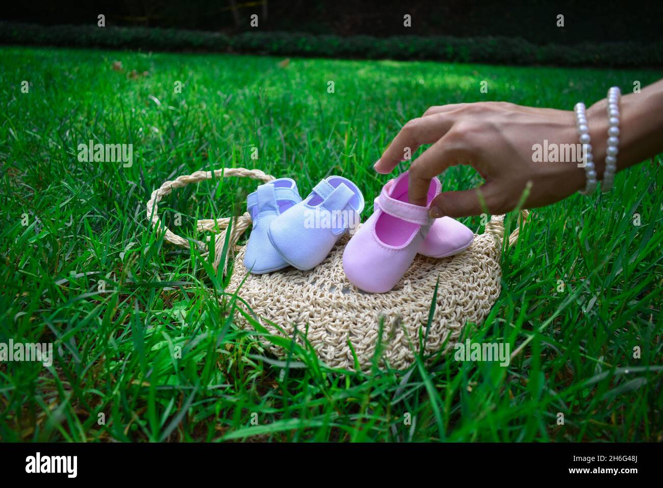 Futura mamma che tiene scarpe rosa per bambini in un parco Foto Stock