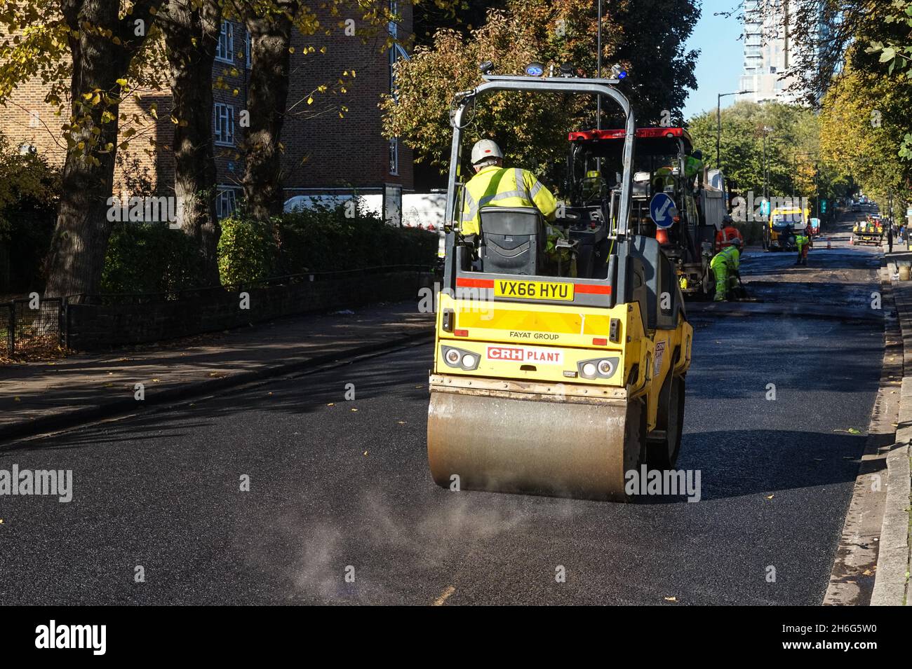 Lavoratori che utilizzano la rulliera stradale in lavori di ripavimentazione stradale a Londra Inghilterra Regno Unito Foto Stock