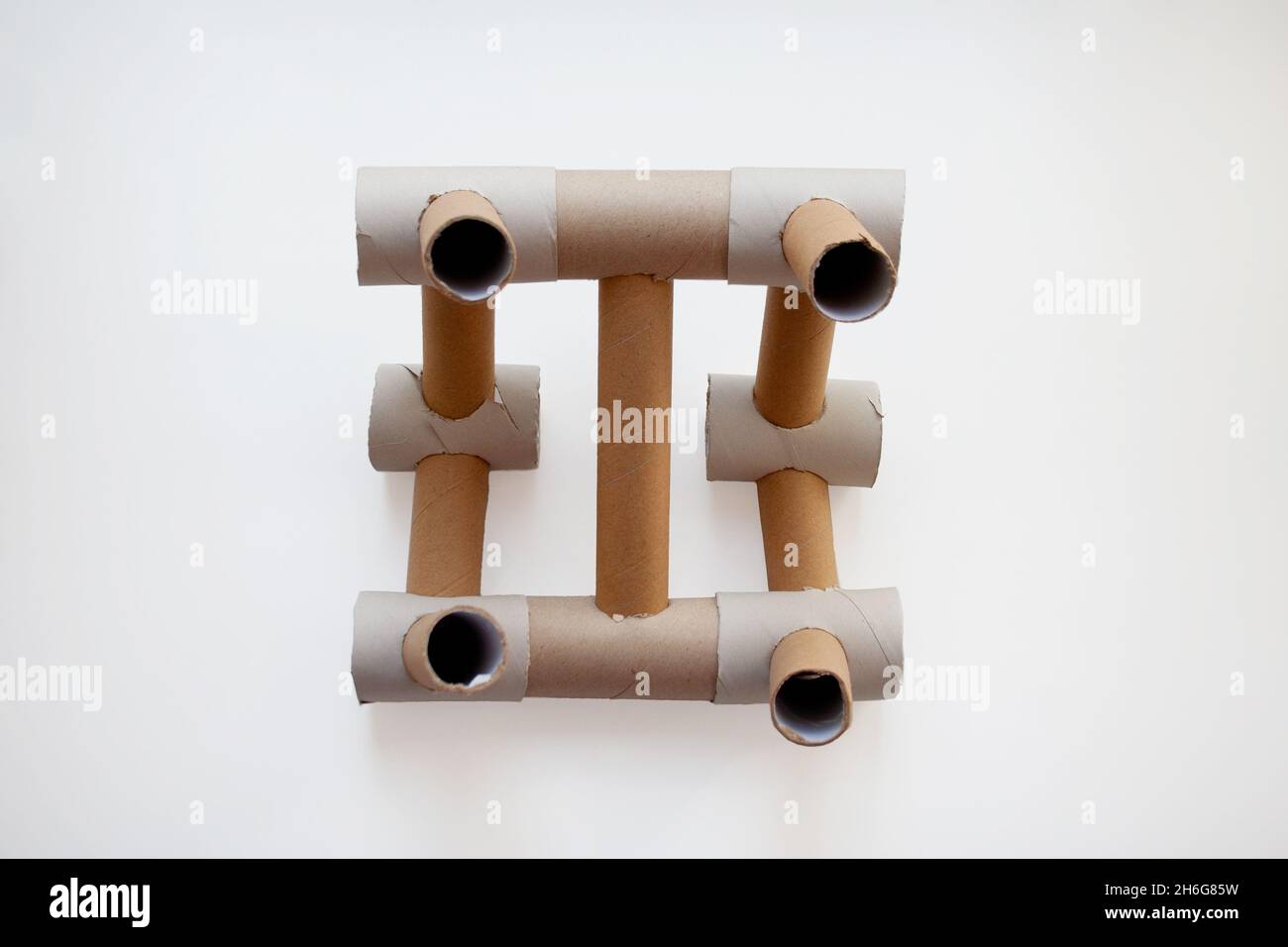 Struttura astratta progettata con tubi di carta di cartone beige isolati su sfondo bianco da un'angolazione elevata Foto Stock