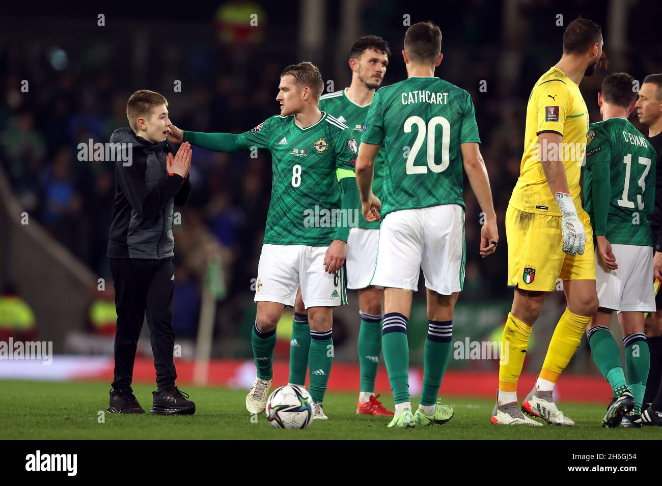 Il capitano dell'Irlanda del Nord Steven Davis viene avvicinato da un giovane invasore di campo dopo il fischio finale, prima di consegnargli la sua fascia capitani dopo la partita di qualificazione della Coppa del mondo FIFA al Windsor Park di Belfast. Data foto: Lunedì 15 novembre 2021. Foto Stock