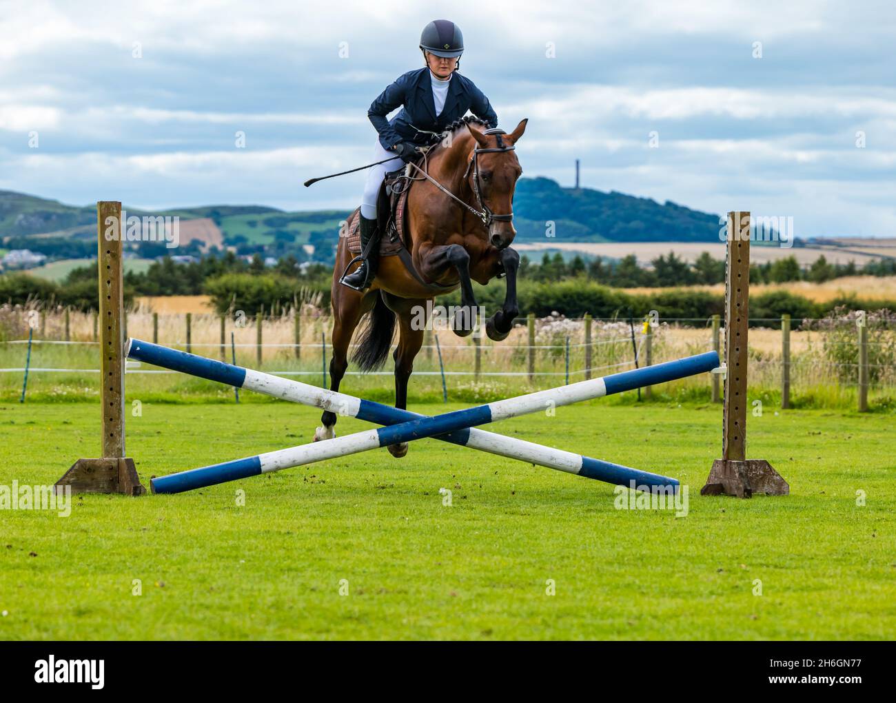 Spettacolo estivo di cavalli con una donna che cavalca un cavallo saltando sopra un cavallo, East Lothian, Scozia, Regno Unito Foto Stock