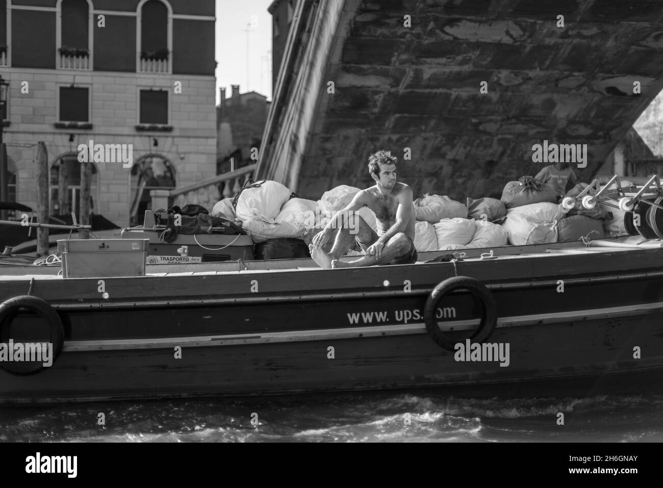 Giovane uomo che lavora su una chiatta USP attraverso i canali di Venezia Foto Stock