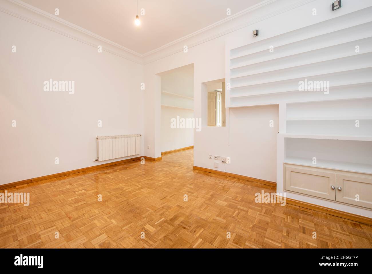 Soggiorno in un edificio d'epoca con pavimenti in parquet, ripiani in gesso e pareti dipinte di bianco in un appartamento per vacanze Foto Stock