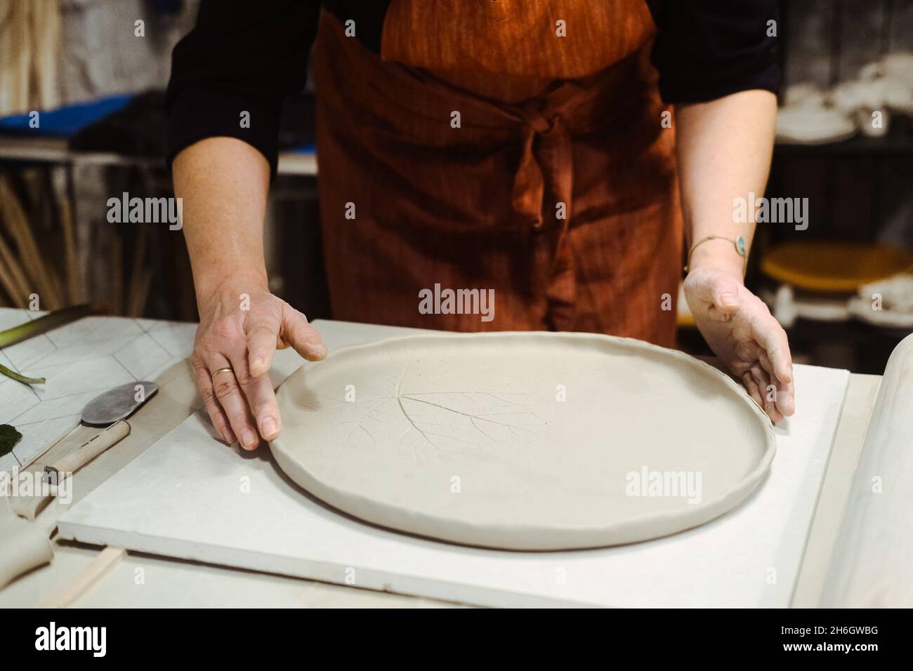 Le mani delle donne lavorano con argilla sul tavolo Foto Stock