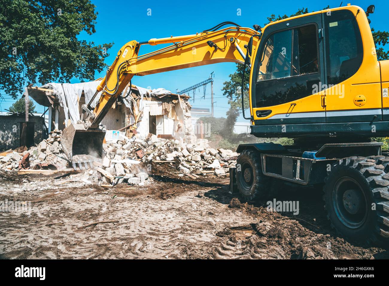 Demolizione di edifici. Processo di smantellamento della casa. L'escavatore rompe il vecchio edificio. Foto Stock