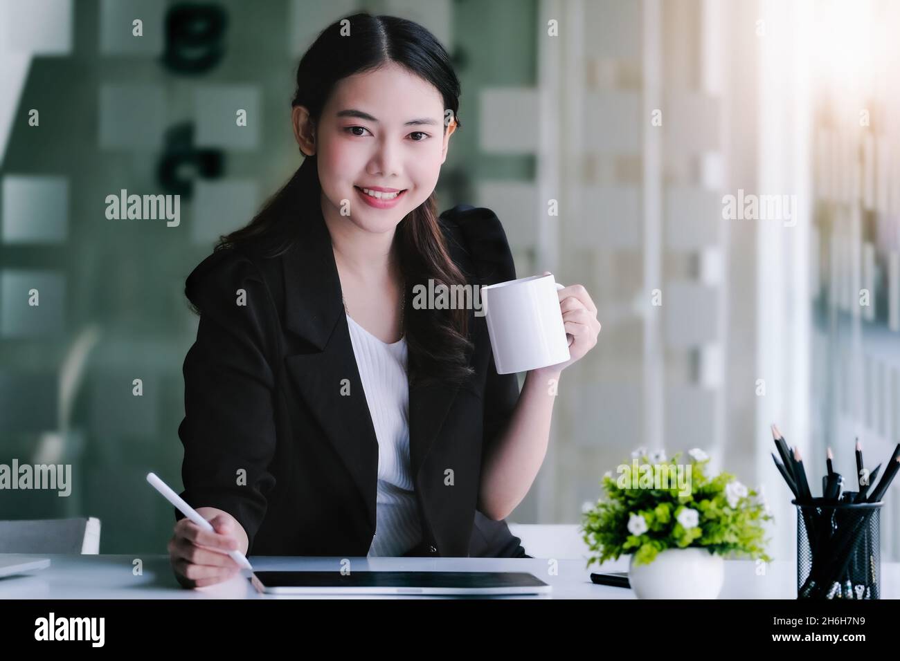 I responsabili di marketing femminili bevono caffè mentre lavorano per ridurre la sonnolenza prima di utilizzare il computer tablet, e le carte di analisi marketing. Foto Stock