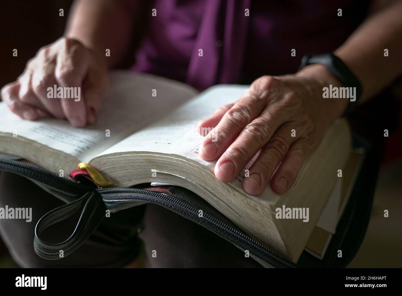 Donna anziana stropicciata mano su un libro aperto. Vista ravvicinata. Foto Stock