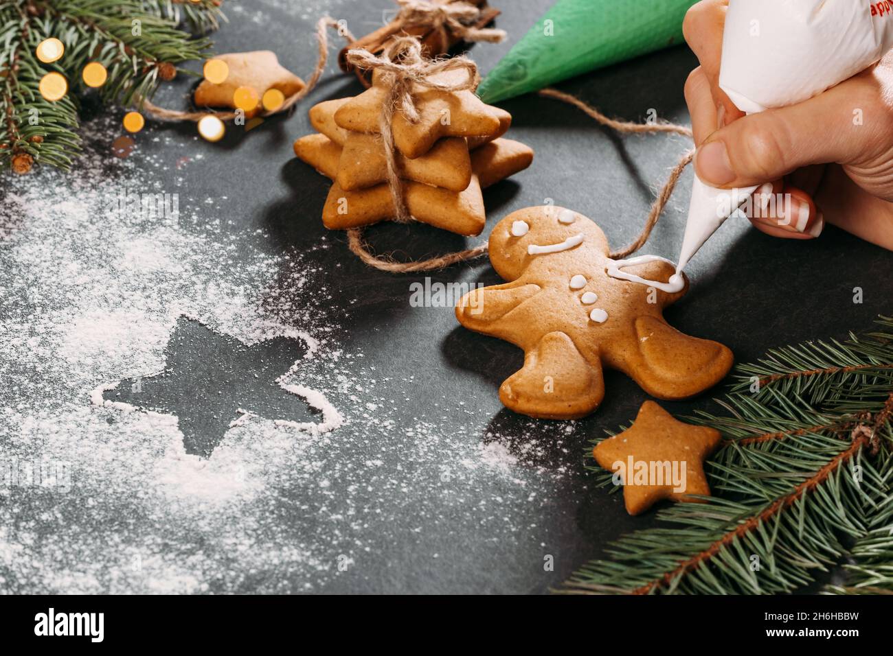 Sfondo di Natale con biscotti fatti in casa di pan di zenzero uomo coperto con glassa sul tavolo nero, spazio copia. Cibo festivo, cartolina, festa Foto Stock