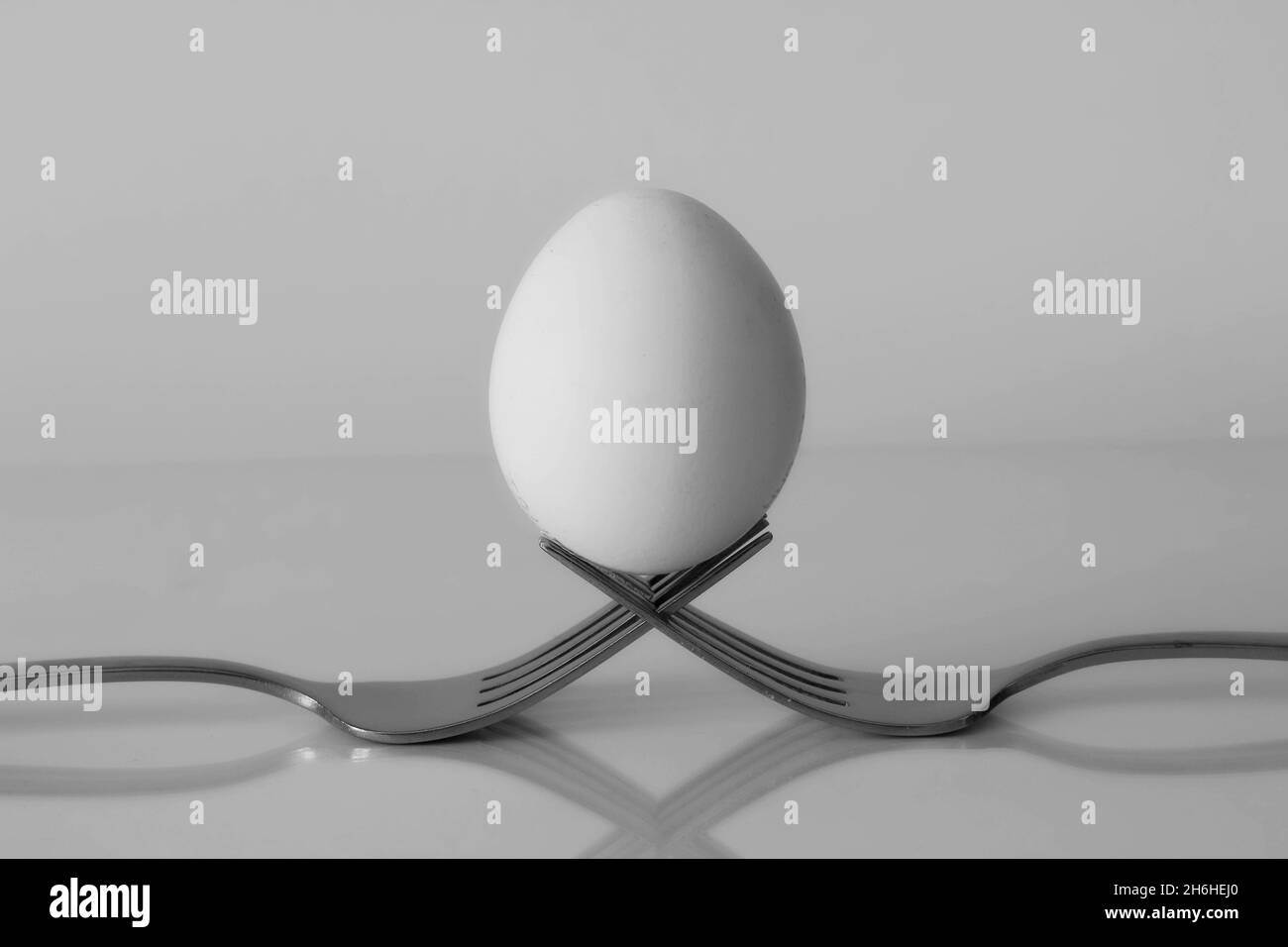 Uovo su due forcelle su sfondo grigio Foto Stock