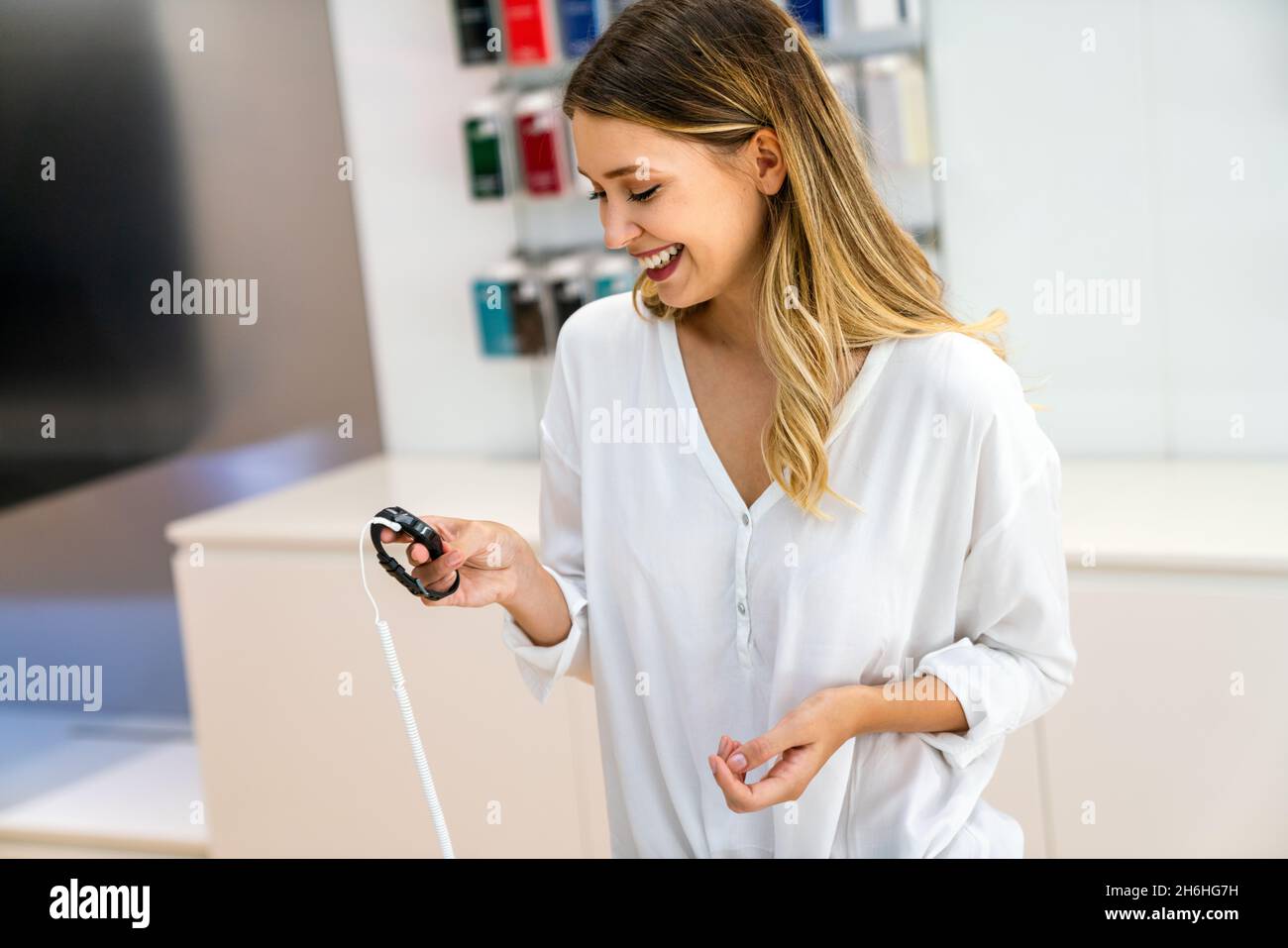 Ritratto di donna sorridente felice che acquista un nuovo smart watch nel negozio tecnologico. Concetto di persone tecnologiche Foto Stock