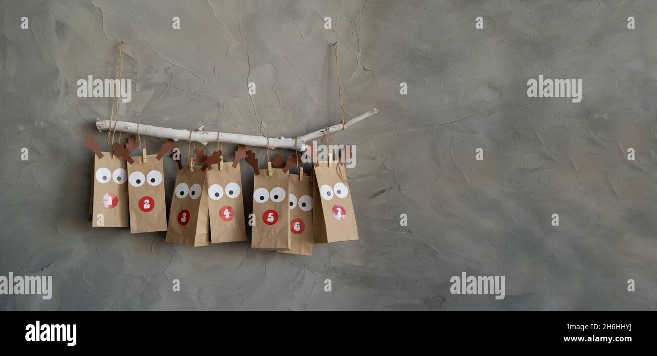calendario dell'avvento fatto a mano con borse di carta e adesivi appesi al muro, sfondo retrò di natale, sorpresa di capodanno. Foto Stock