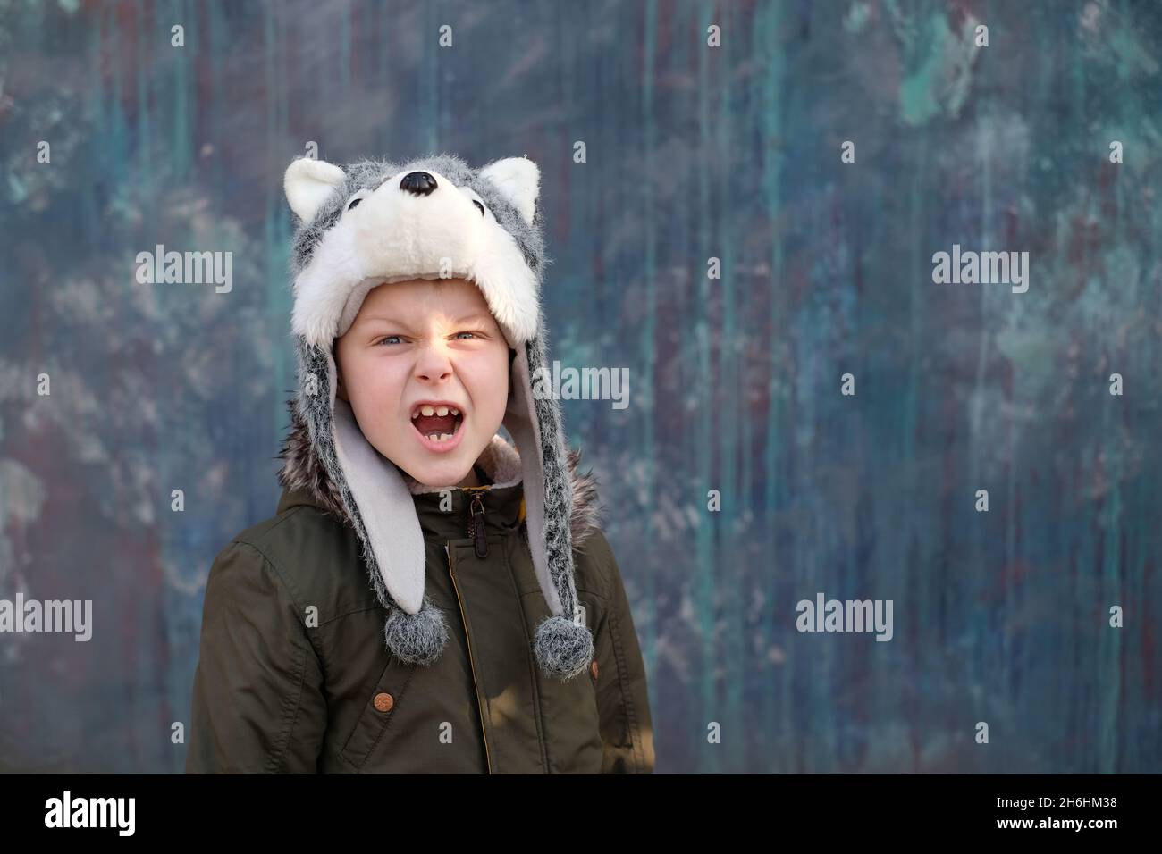 Il ruggito di un lupo. Bambino in un cappello lupo su sfondo grigio, all'aperto. Foto di alta qualità Foto Stock