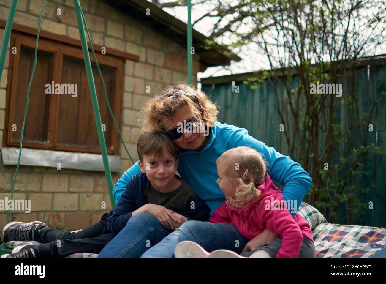 Nonna e i suoi due nipoti che si divertono in un'altalena, nonno e nipote amano la loro nonna. Outdors rilassante nella campagna della nonna hou Foto Stock