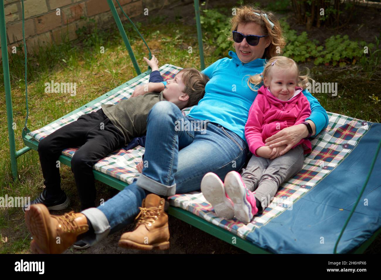 Nonna e i suoi due nipoti che si divertono in un'altalena, nonno e nipote amano la loro nonna. Outdors rilassante nella campagna della nonna hou Foto Stock
